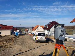 Vermessung in einem Wohngebiet mit Firmenfahrzeug im Vordergrund